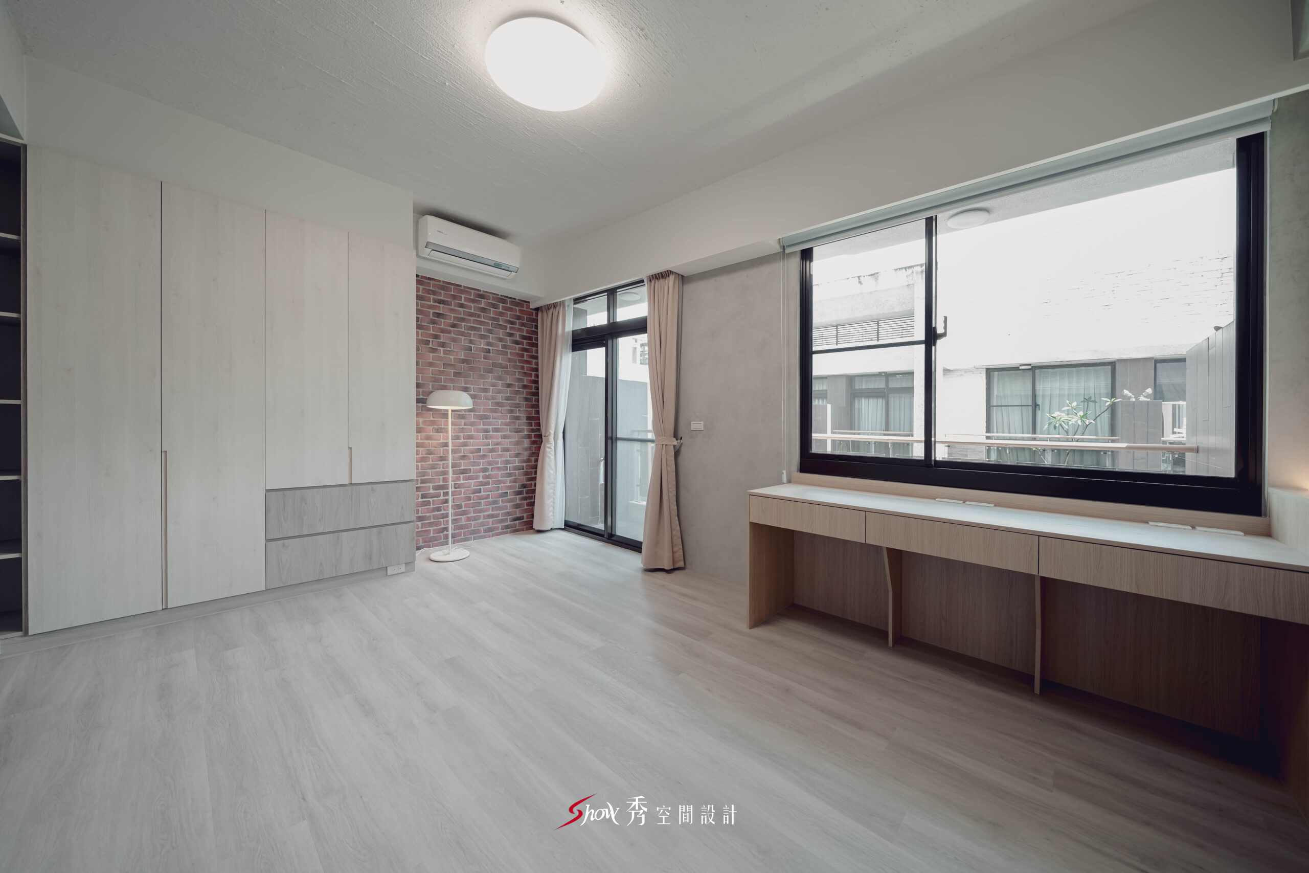 台南善化透天老屋翻新主臥全景，結合系統衣櫃、窗邊桌面、紅磚端景牆與大面採光，呈現現代簡約混搭輕工業風格。