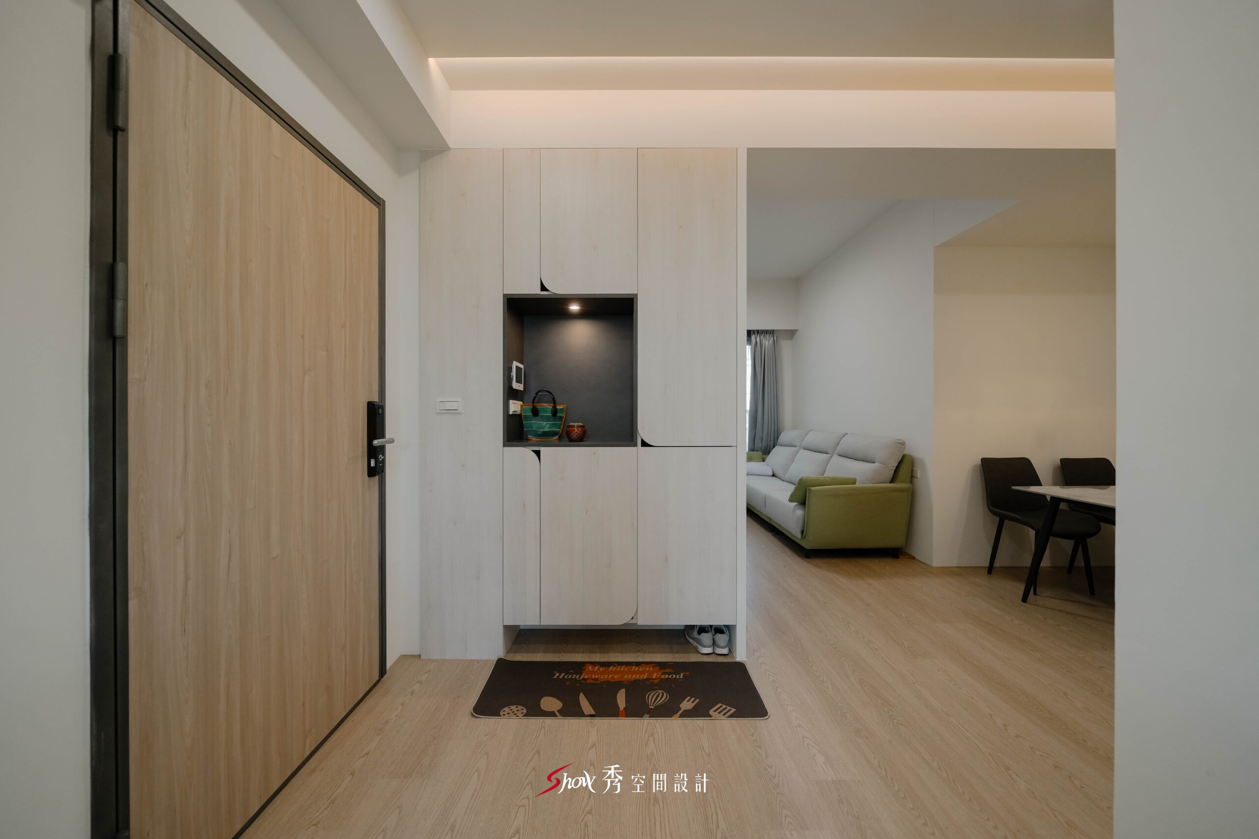 玄關收納櫃正面視角，淺木門片搭配展示燈光