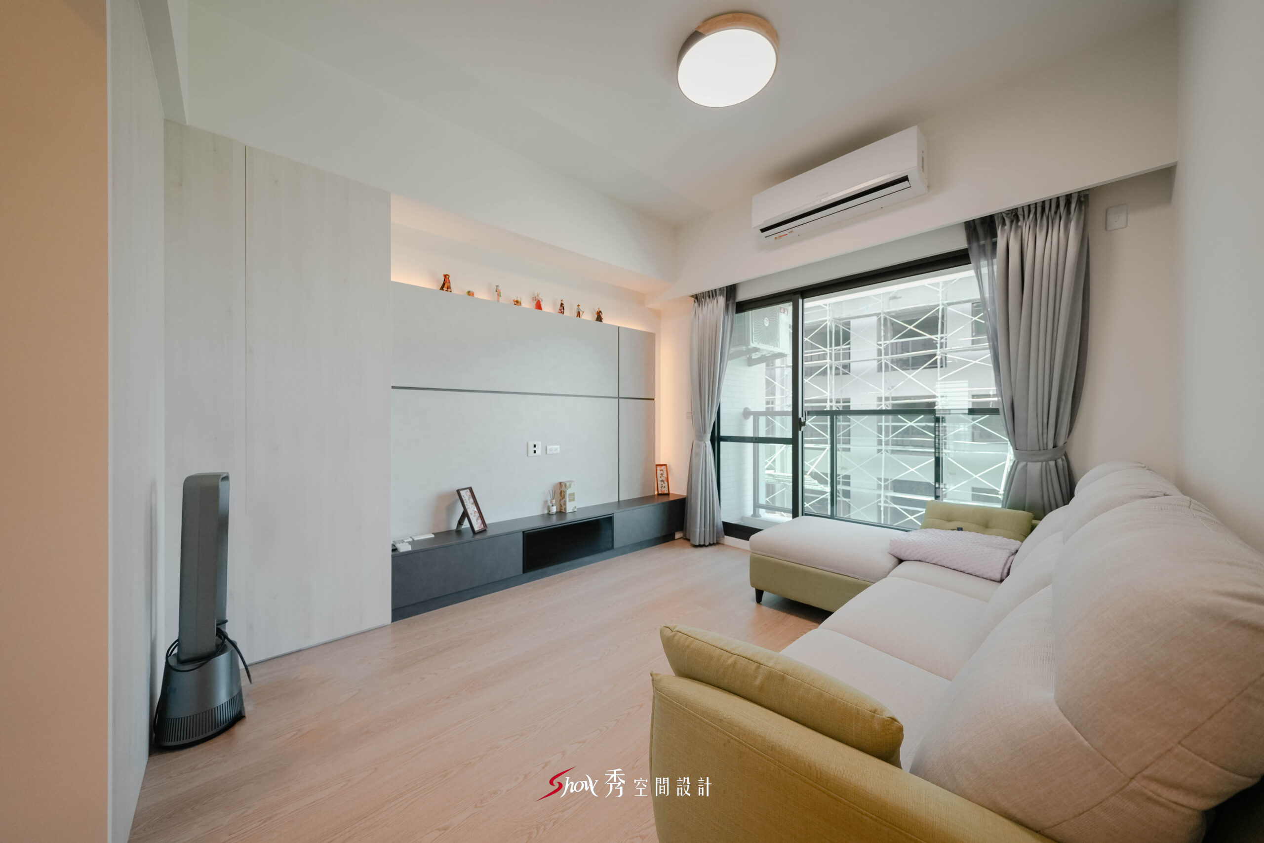 台南室內設計客廳空間，灰階電視牆搭配淺木地板與L型沙發