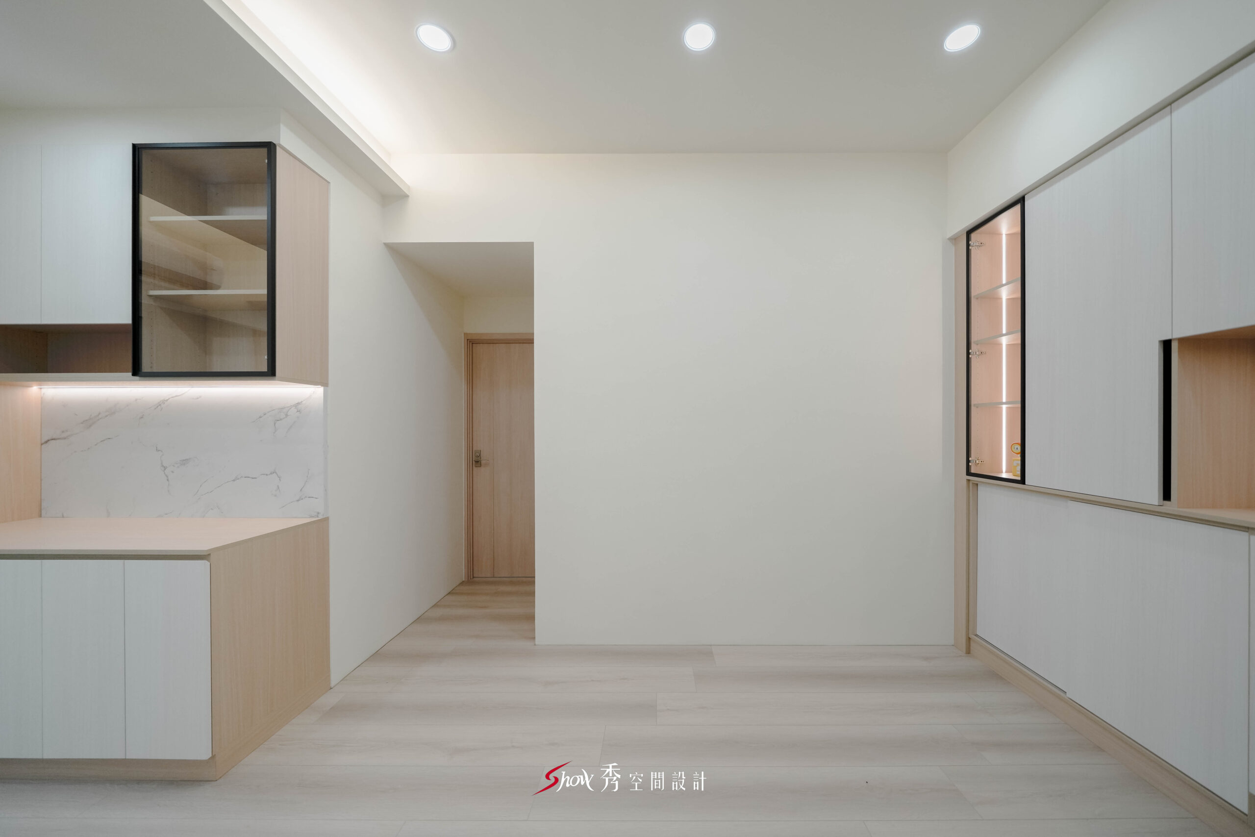台南新市室內設計公共空間，配置淺木餐櫃、黑框玻璃展示櫃、白色收納櫃與石紋背板，打造明亮簡約的居家機能。