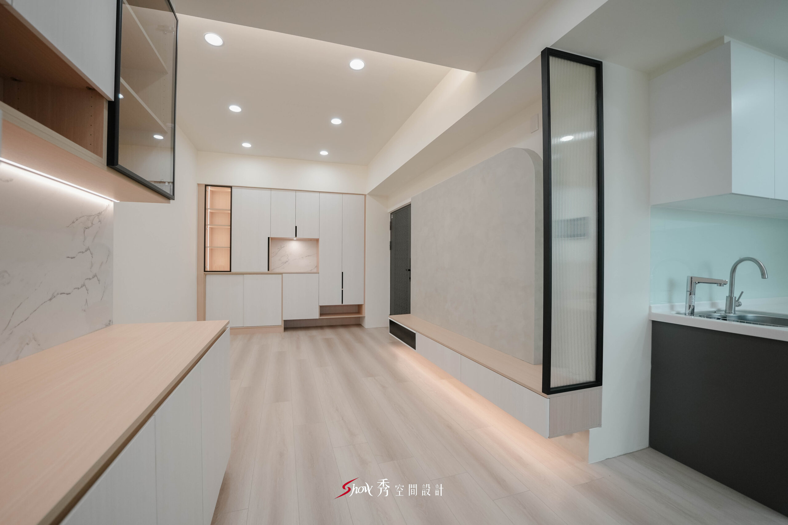 台南新市室內設計案，餐邊櫃、電視牆、長虹玻璃隔屏與開放式廚房形成完整公共空間。