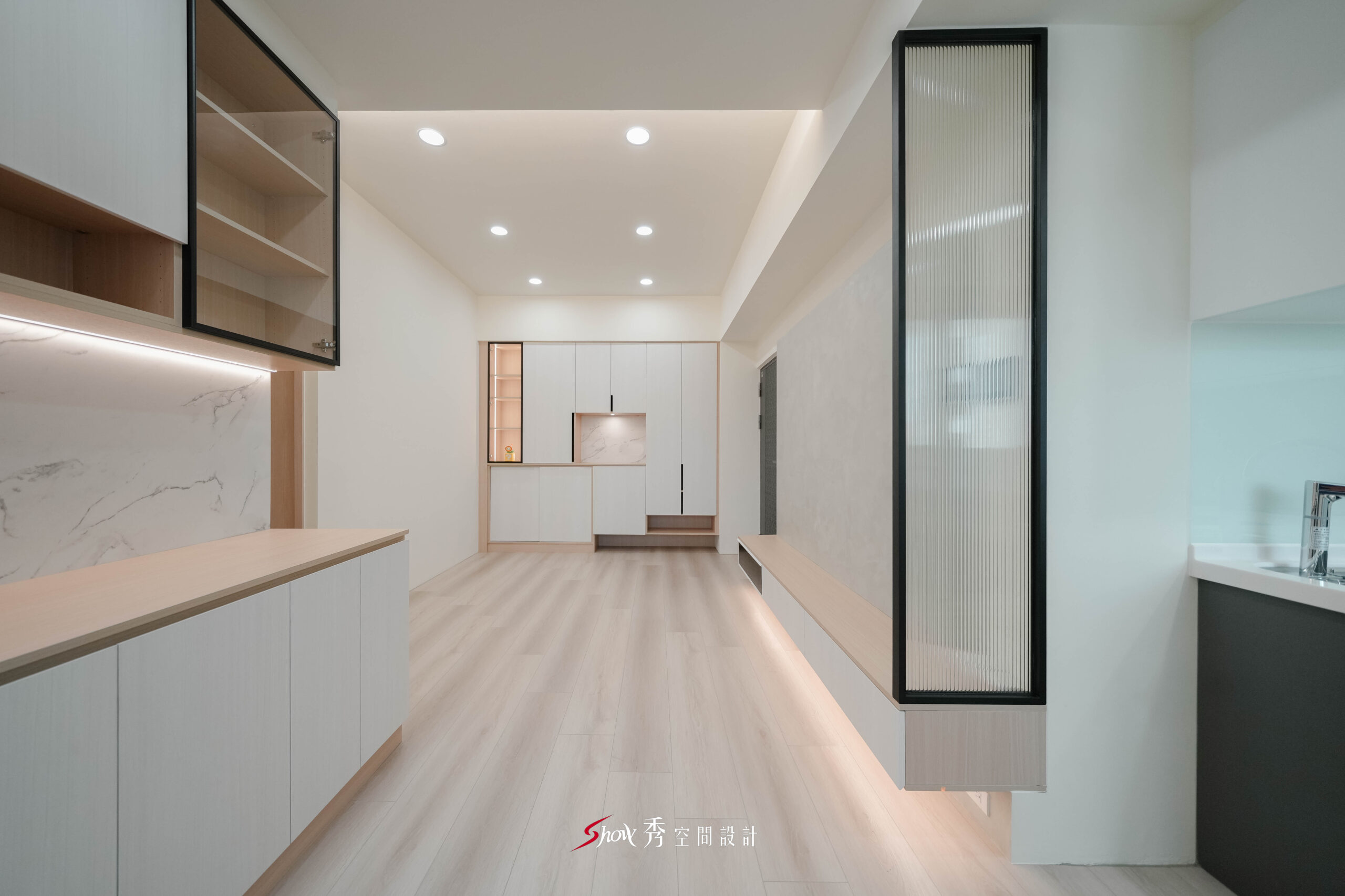 台南新市室內設計案，淺木紋地板搭配白色收納櫃、玻璃展示櫃與開放式客廳動線。