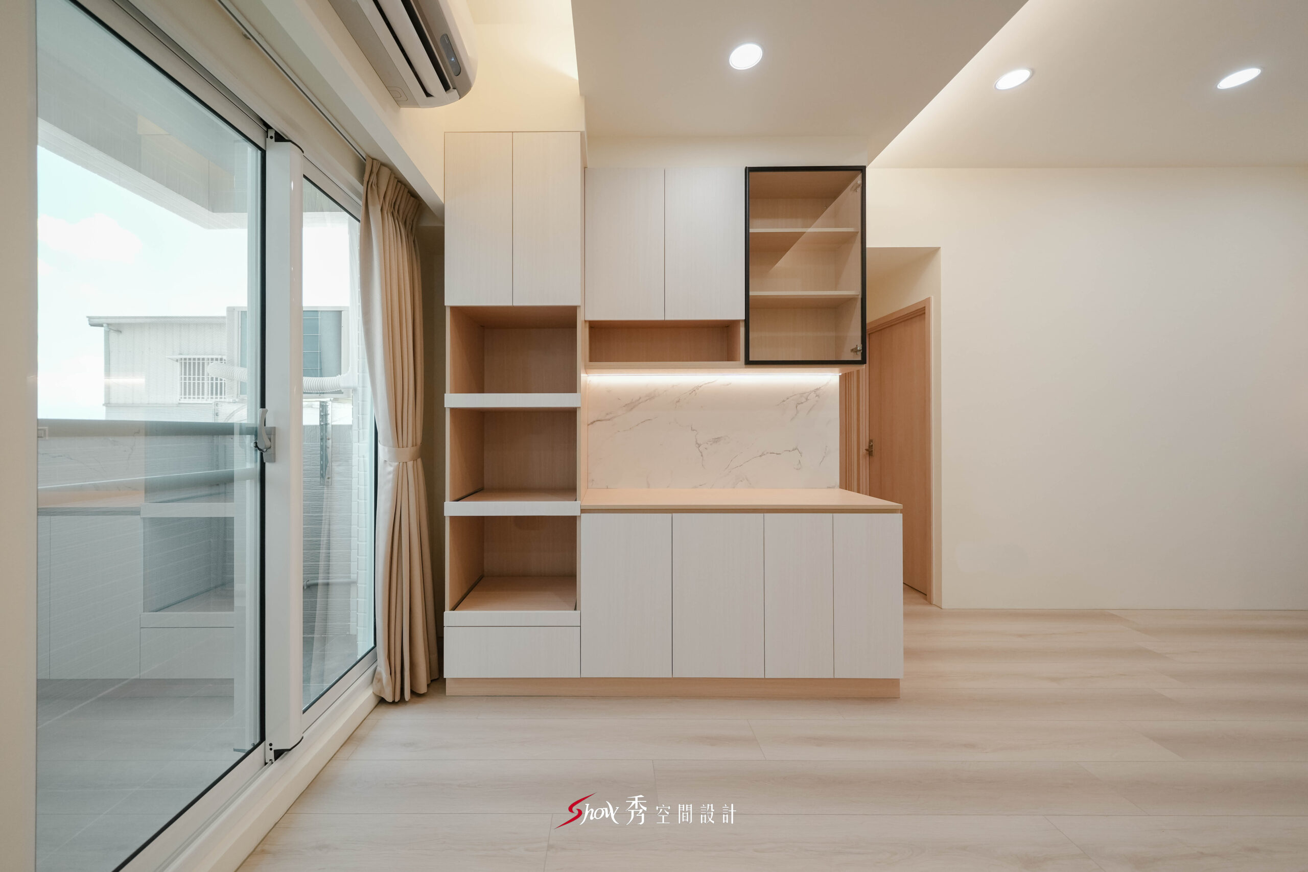 台南新市室內設計案，餐邊收納櫃結合玻璃展示櫃、石紋背板與陽台自然採光。