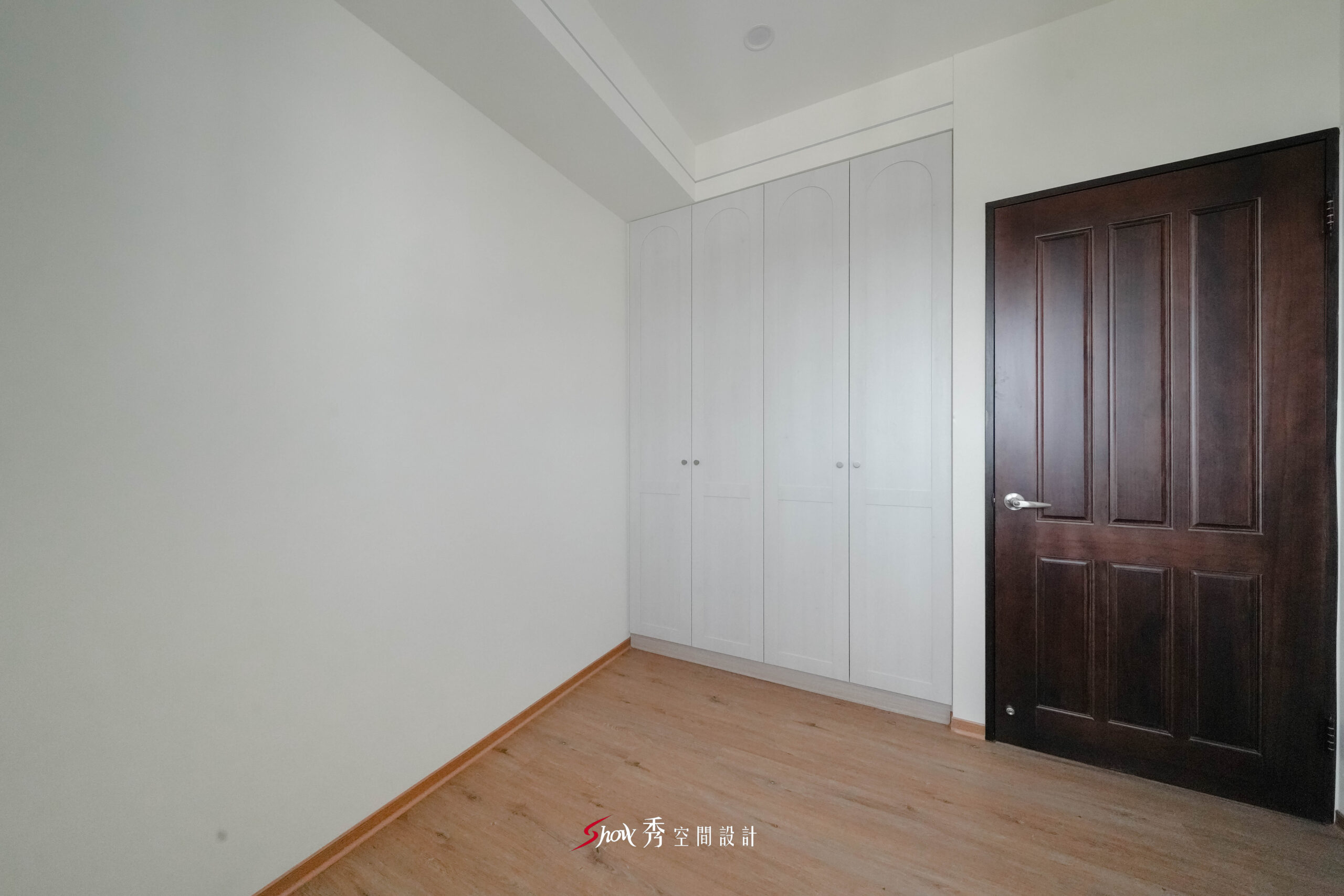 次臥採白色系統衣櫃搭配深木色房門與木質地板，塑造溫潤自然的臥室氛圍。
