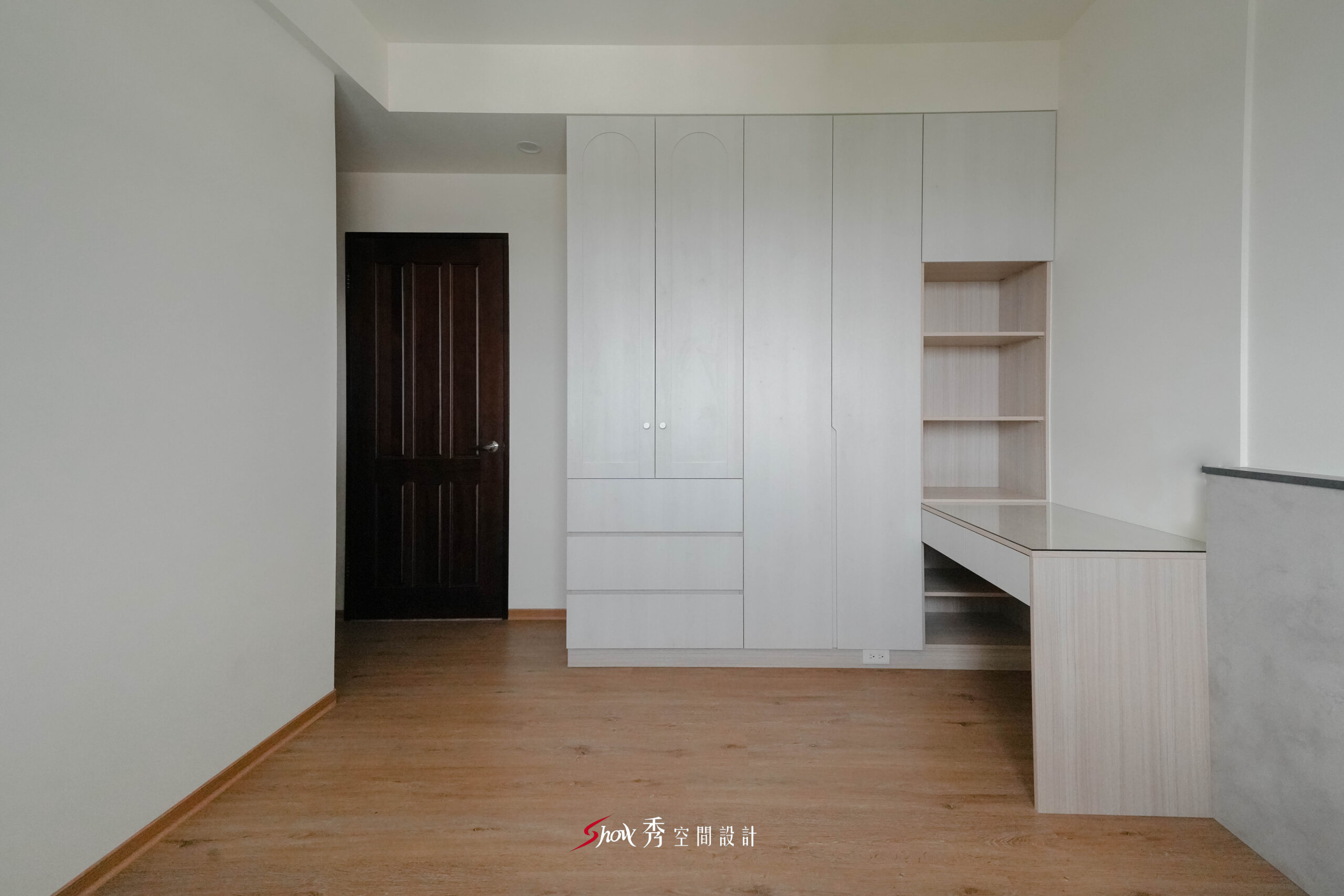 臥室採用整排白色衣櫃搭配書桌平台與淺木地板，保留寬敞走道與明亮空間感。