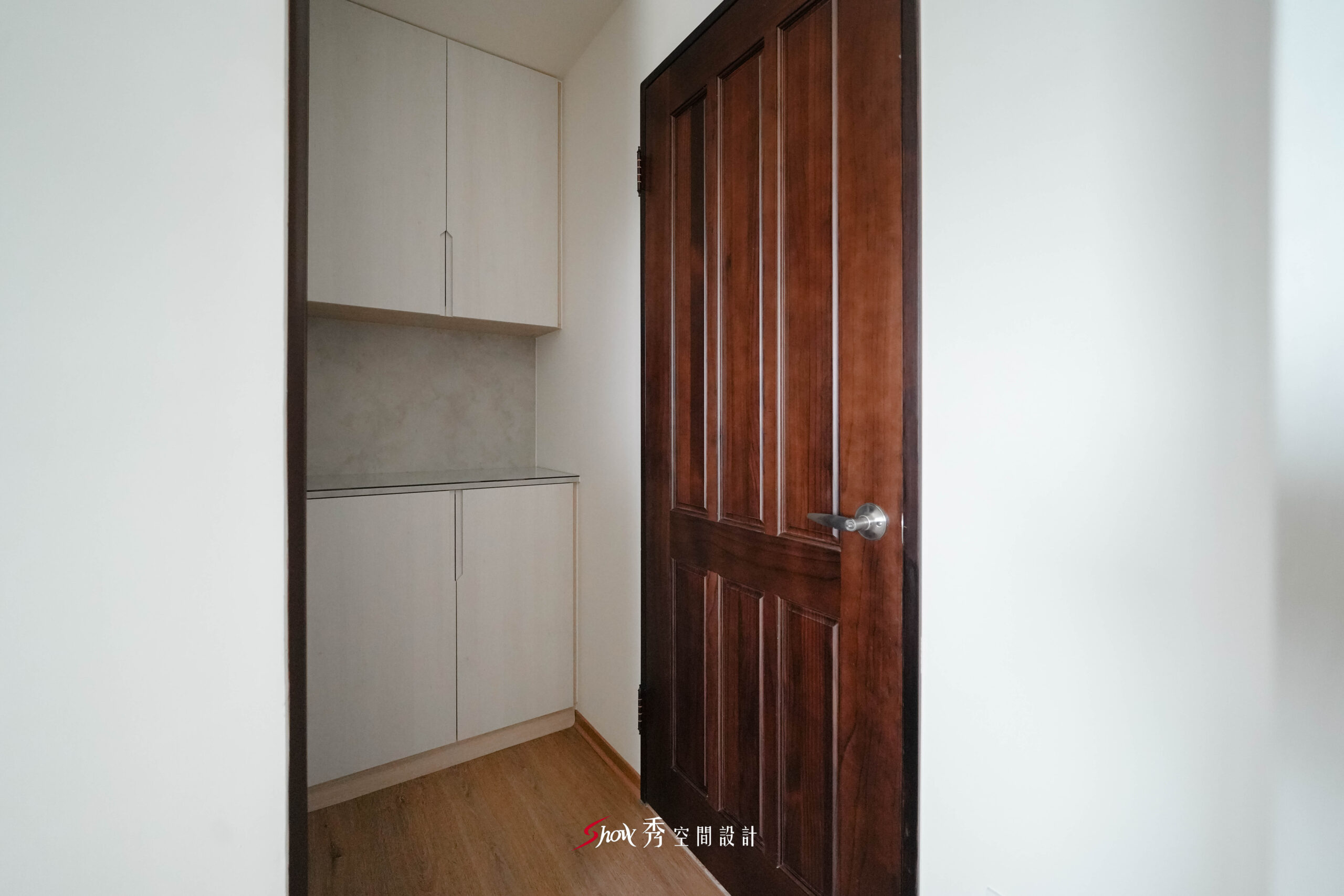 玄關旁規劃上下櫃收納區，搭配深色木門與灰色壁面，形成實用簡潔的入口機能。