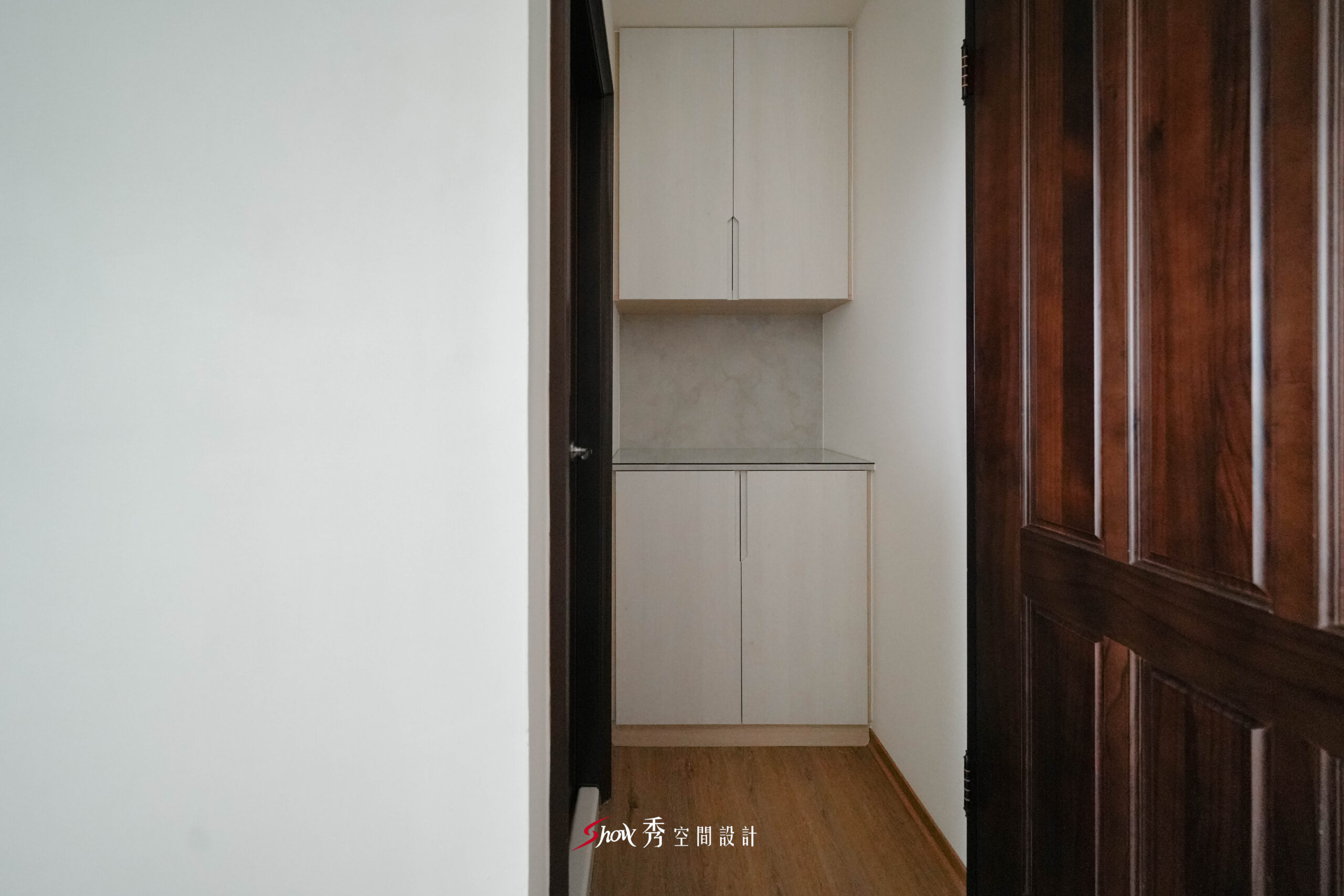 玄關收納櫃以淺木色門板搭配灰色背牆與石紋檯面，展現簡約俐落的入口設計。