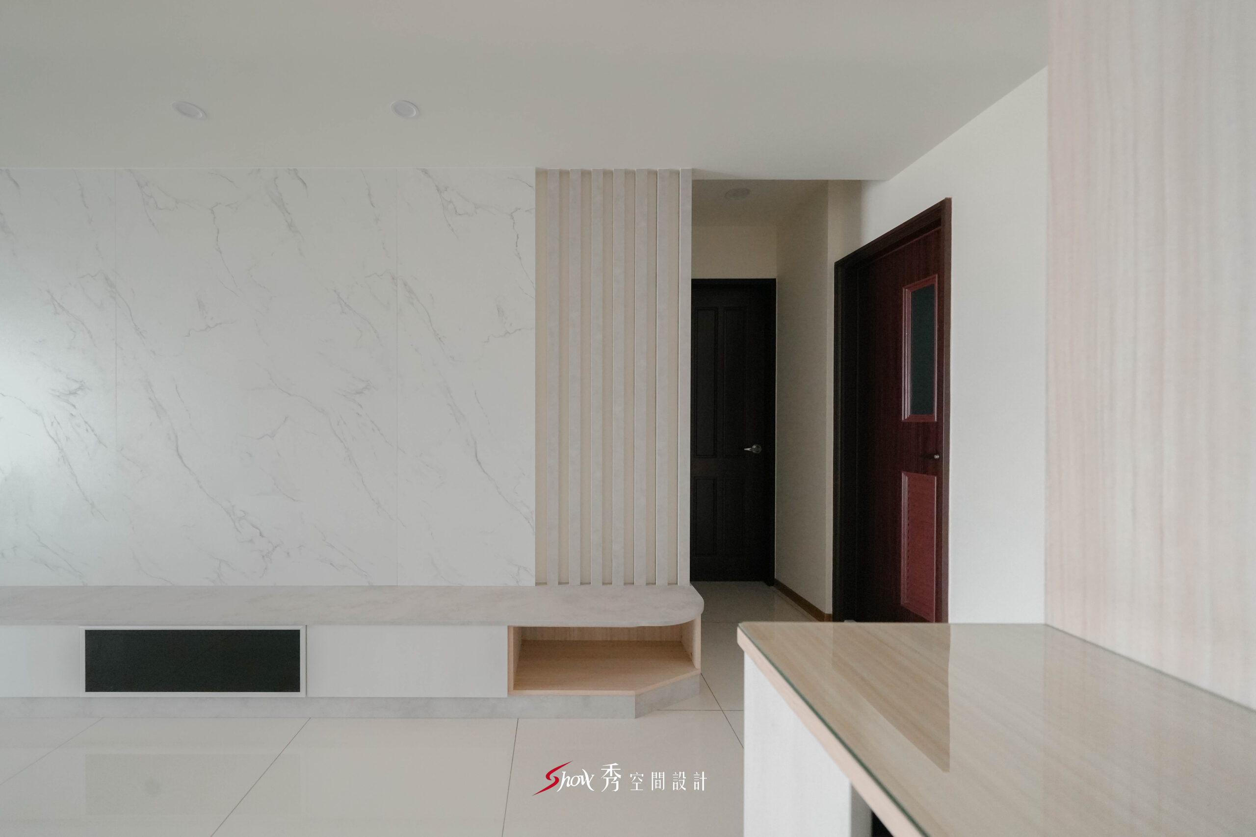 電視牆以大理石紋搭配垂直格柵設計，結合懸浮收納櫃提升空間層次。