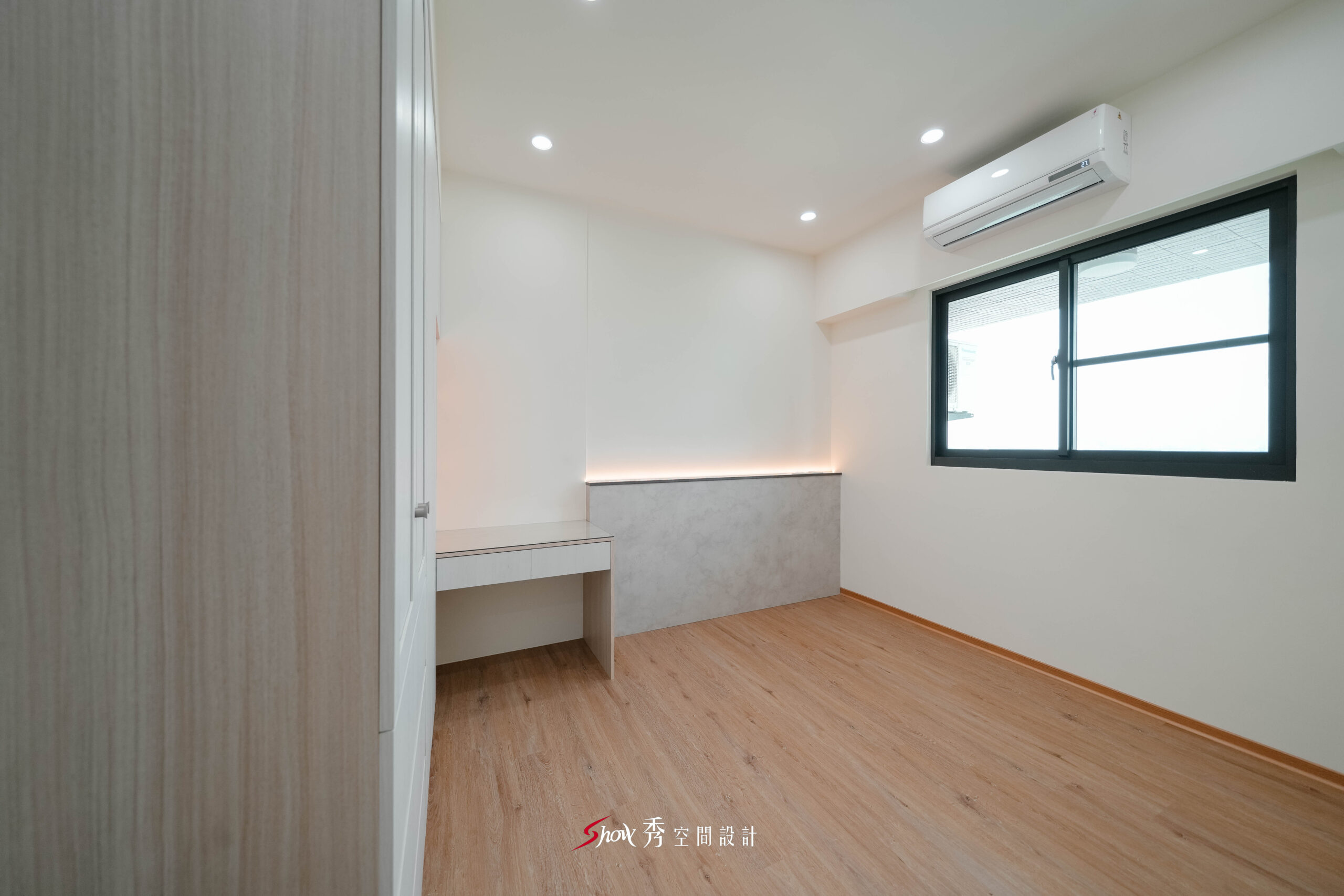 臥室採木地板搭配書桌與半高牆設計，並引入自然光營造舒適空間。