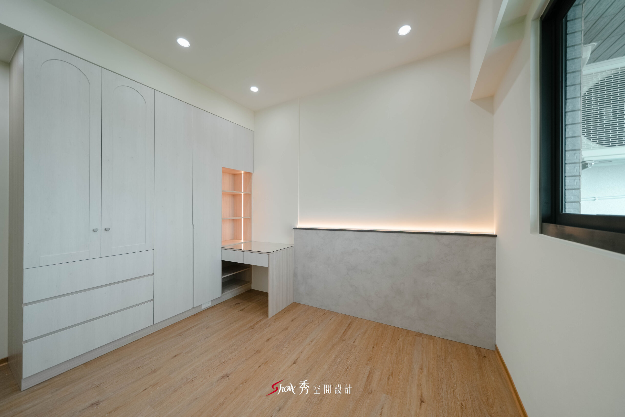 臥室以整面衣櫃與書桌平台結合，搭配灰色低牆與間接照明設計。