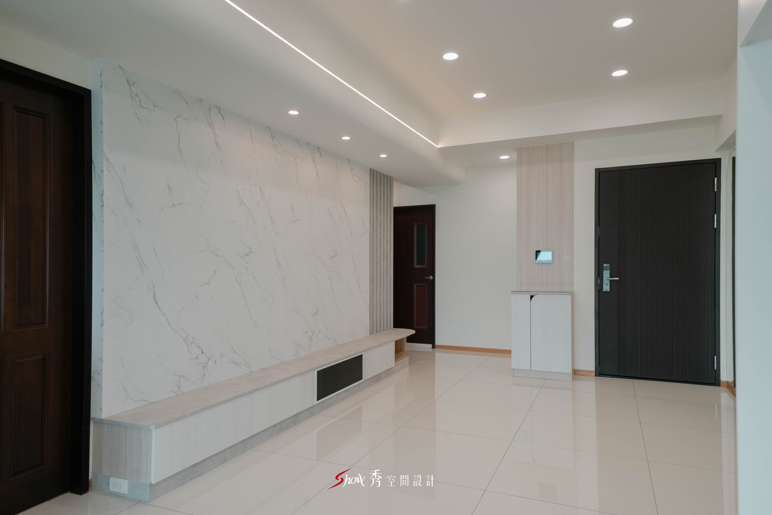 客廳入口區結合電視牆與玄關櫃設計，打造簡約俐落的居家入口視覺。