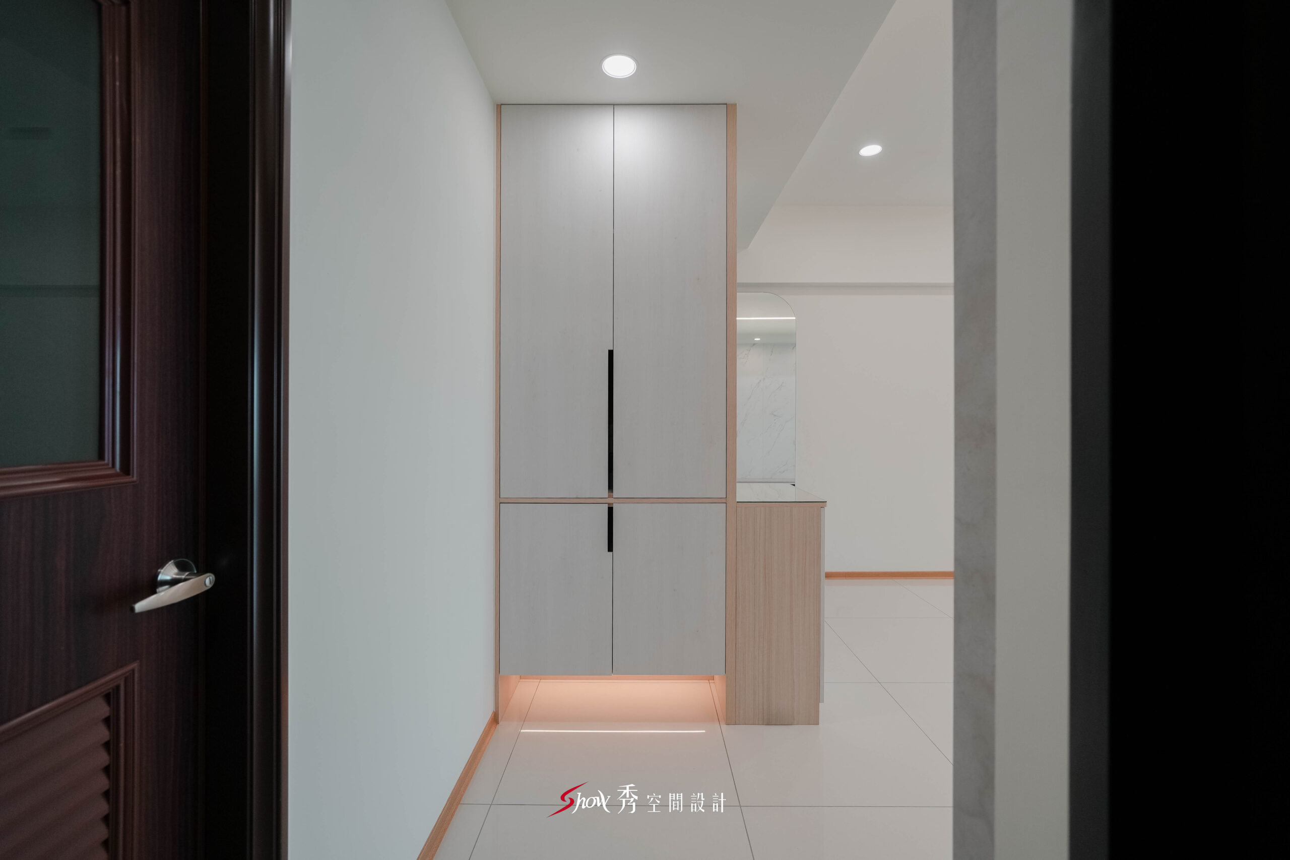 玄關區設計高櫃與懸浮燈光，結合木質元素營造溫潤入門氛圍。