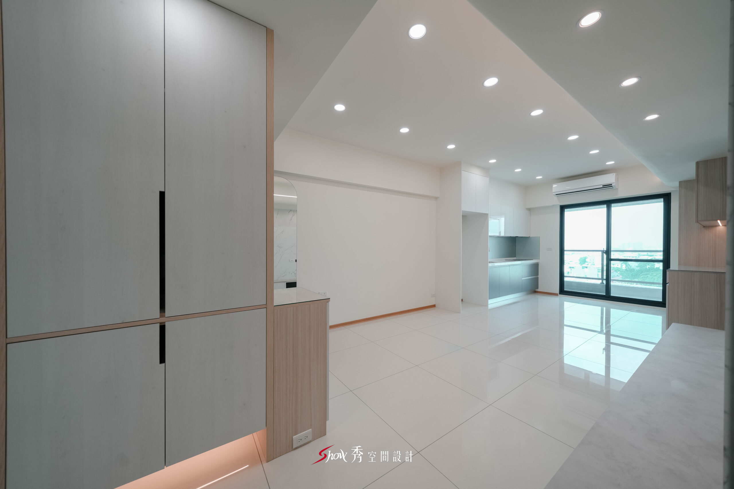 開放式客餐廳結合玄關收納櫃與廚房區域，採白色地坪與淺木元素打造明亮空間。