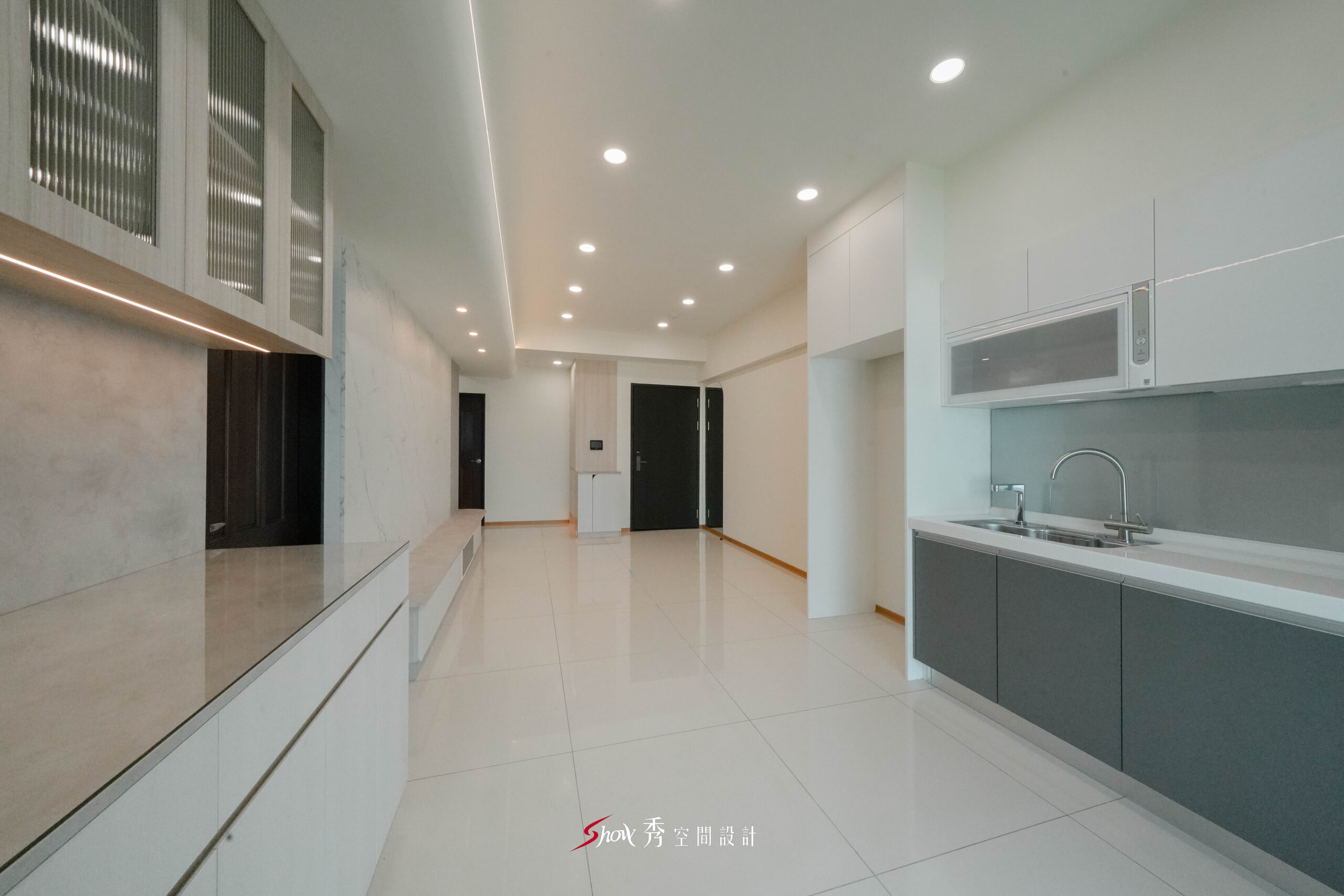 客廳延伸至廚房區域，搭配吊櫃與中島檯面設計，呈現流暢動線配置。