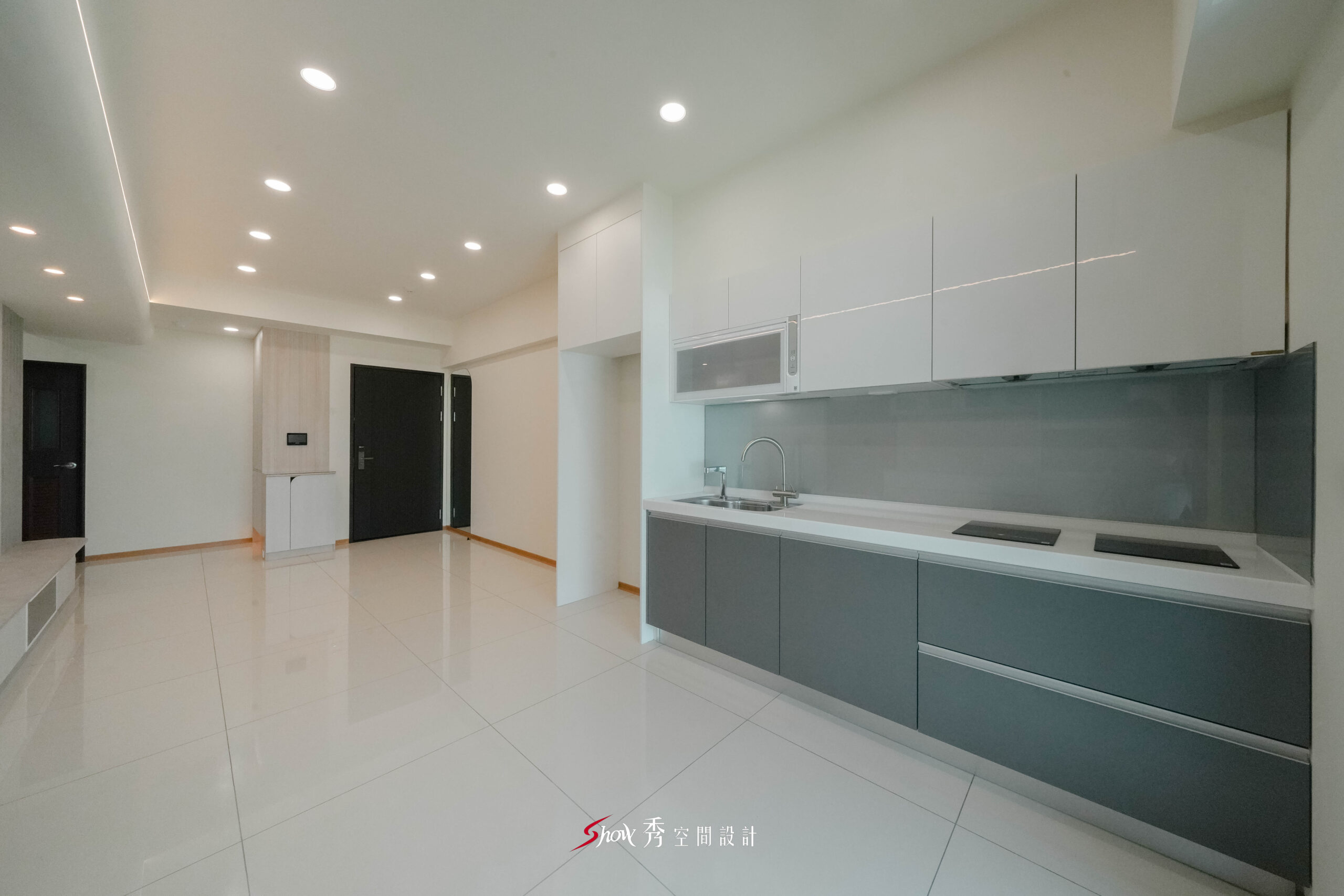 開放式廚房搭配灰色下櫃與白色吊櫃設計，與客廳空間連續延伸。