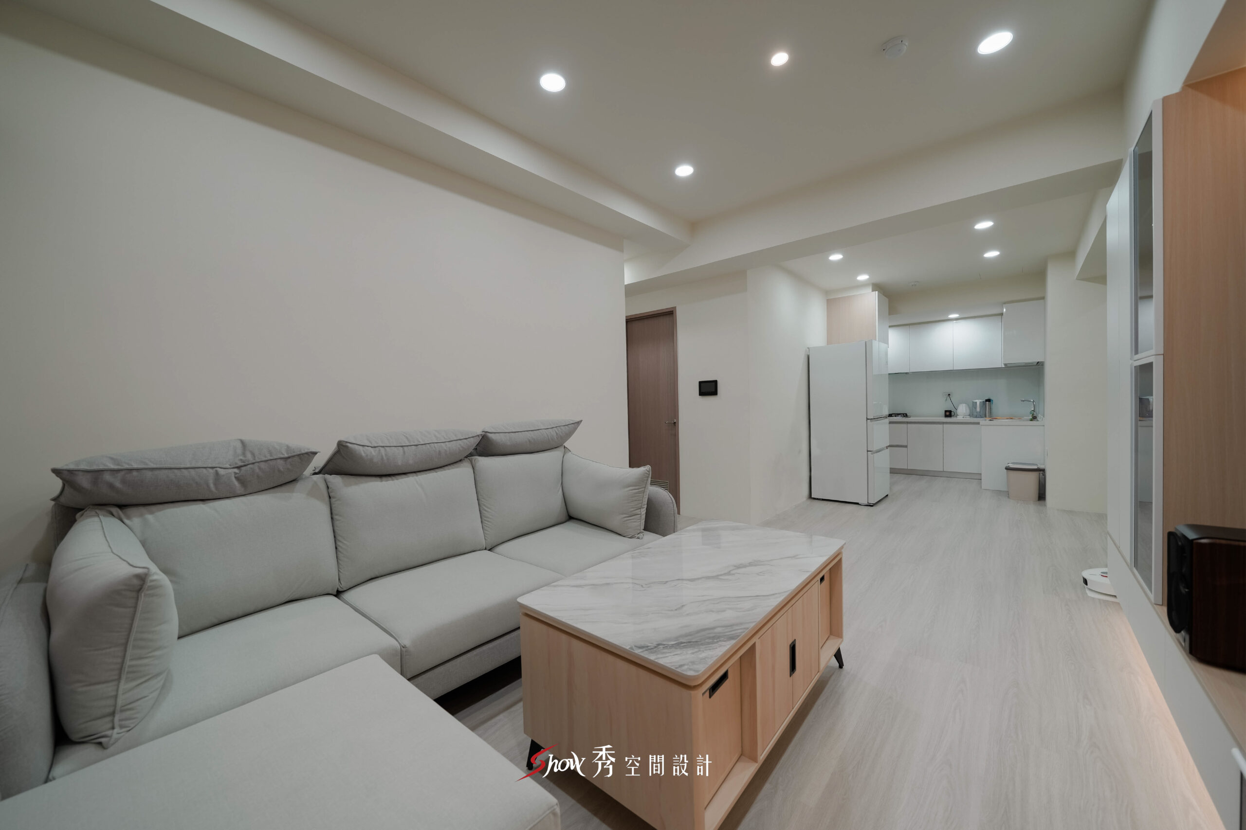 台南室內設計客廳空間，灰色L型沙發搭配石紋茶几與淺木紋地板，呈現簡約舒適氛圍。