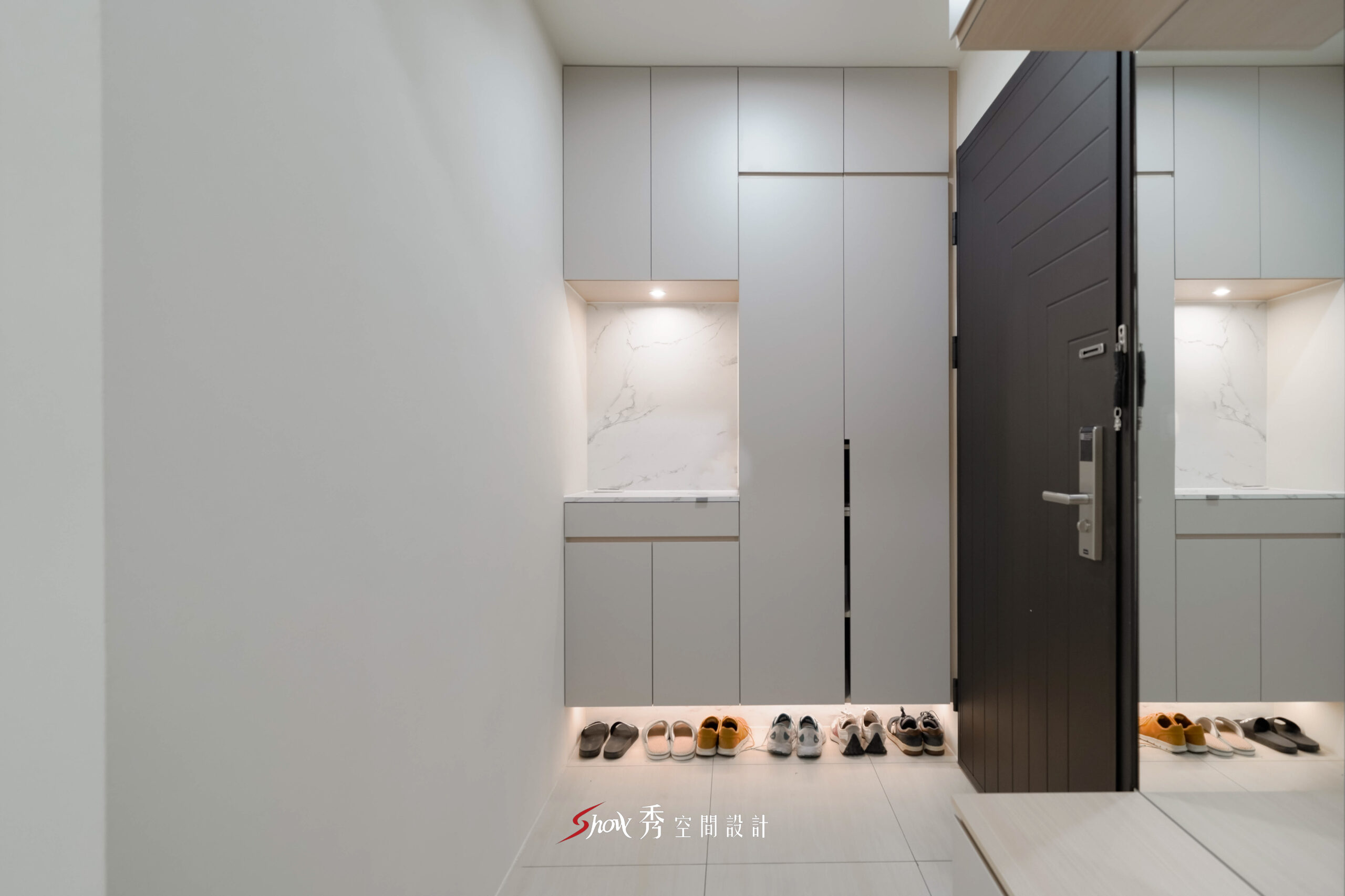 台南現代簡約玄關空間，以灰色系統鞋櫃與間接照明打造俐落收納設計。