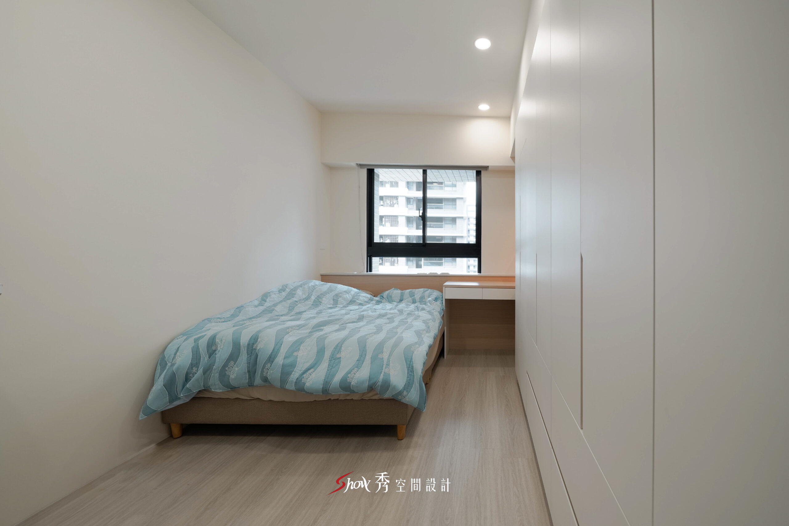 台南臥室設計，以白色系統櫃、木質書桌與大面採光打造簡約舒適睡眠空間。