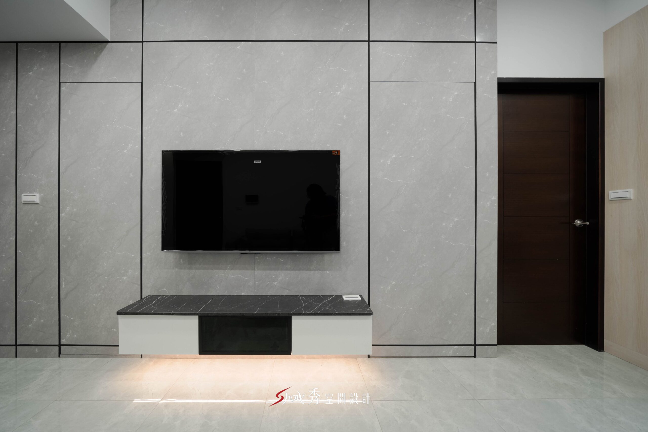 灰色大板磚電視牆搭配懸浮電視櫃與深色木門的客廳空間設計